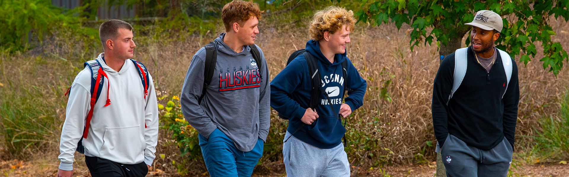 four uconn students walking and wearing uconn sweatshirts four uconn students walking and wearing uconn sweatshirts